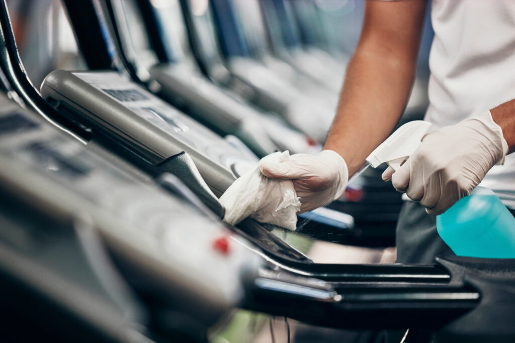 Cleaning, treadmill and sanitizing gym equipment for bacteria, germs or protection from covid. D.