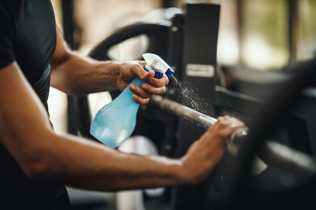 Shot of a muscular unrecognizable man cleaning fitness gym equipment before workout