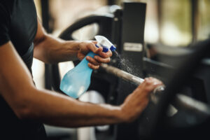 Shot of a muscular unrecognizable man cleaning fitness gym equipment before workout